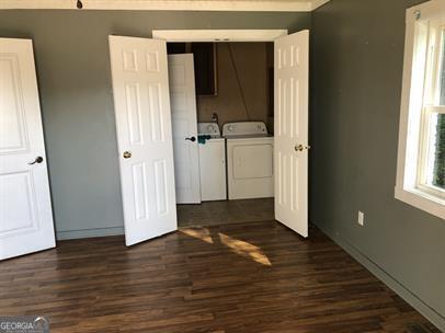 unfurnished bedroom featuring washing machine and dryer and dark hardwood / wood-style flooring