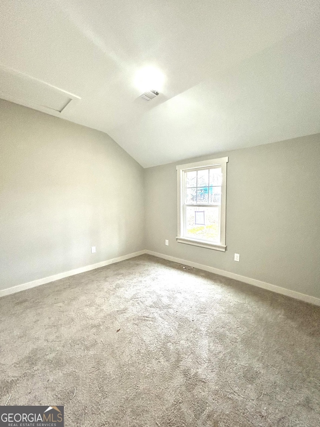 spare room with a textured ceiling, carpet flooring, and lofted ceiling