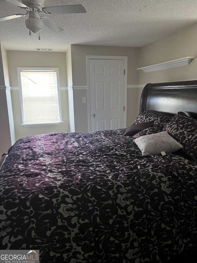 bedroom with ceiling fan and a textured ceiling