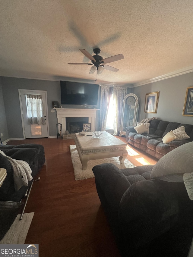 living room featuring ceiling fan, dark hardwood / wood-style floors, crown molding, and a textured ceiling