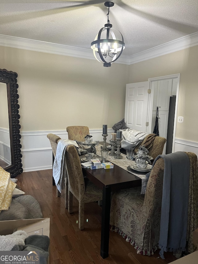 dining space with a textured ceiling, crown molding, and a notable chandelier