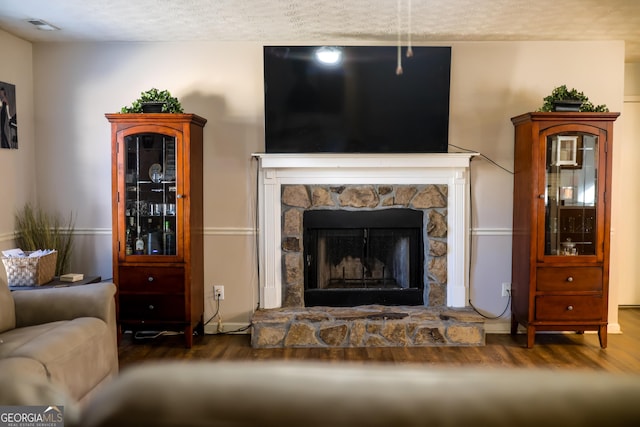 living room featuring dark wood-type flooring and a stone fireplace