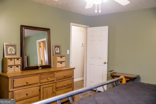 bedroom with ceiling fan, dark hardwood / wood-style flooring, and a textured ceiling