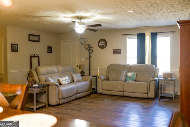 living room featuring ceiling fan, a textured ceiling, and dark hardwood / wood-style floors