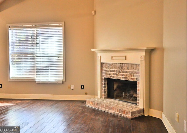 unfurnished living room with dark wood-type flooring and a brick fireplace