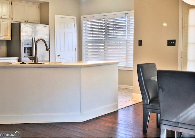 kitchen with dark wood-type flooring, white cabinets, and stainless steel fridge