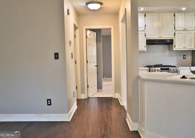 corridor with dark hardwood / wood-style floors and a textured ceiling