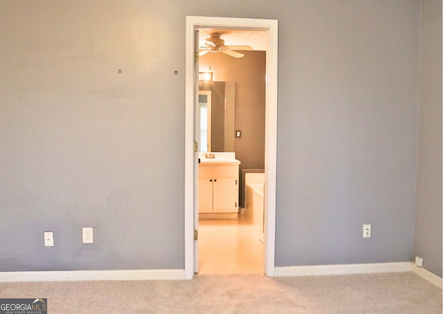 empty room with light carpet, ceiling fan, and sink