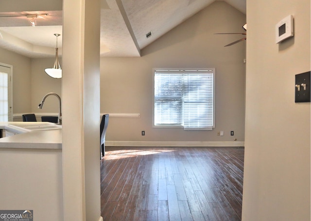 kitchen featuring ceiling fan, decorative light fixtures, dark wood-type flooring, lofted ceiling, and sink