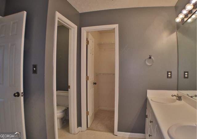 bathroom featuring vanity, a textured ceiling, and toilet