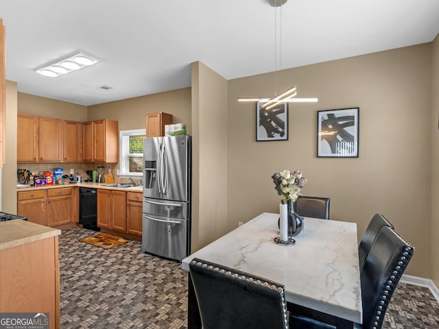 kitchen featuring stainless steel refrigerator with ice dispenser, decorative backsplash, sink, black dishwasher, and hanging light fixtures