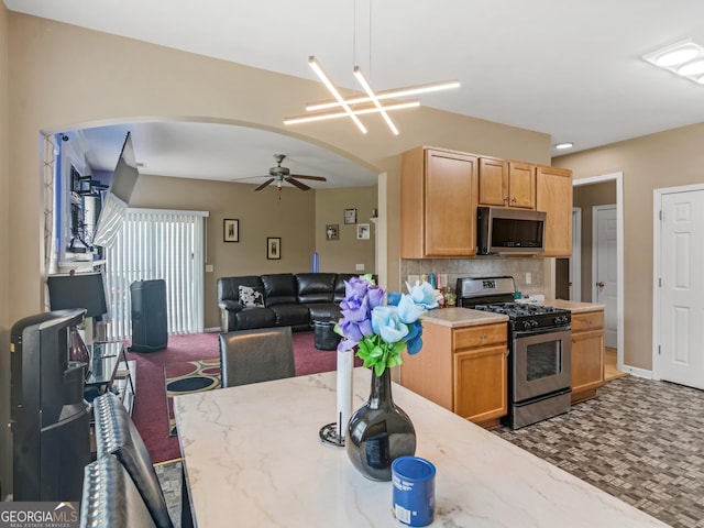 kitchen featuring decorative light fixtures, backsplash, ceiling fan with notable chandelier, and stainless steel appliances