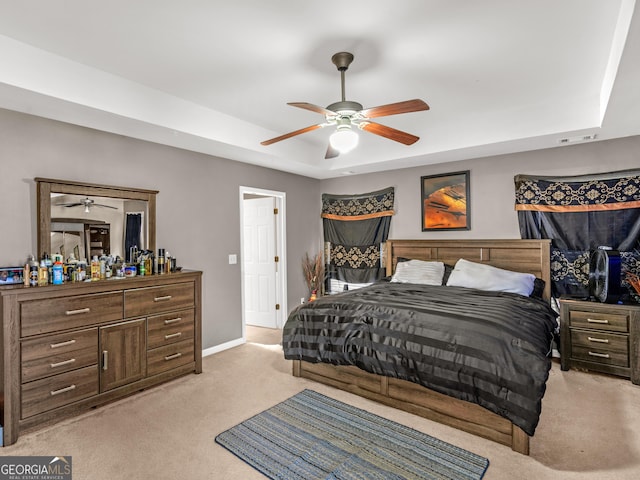 carpeted bedroom featuring ceiling fan and a raised ceiling