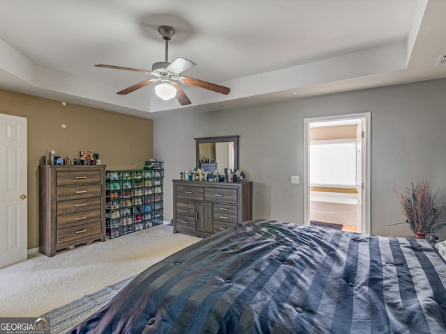 carpeted bedroom featuring ceiling fan, connected bathroom, and a tray ceiling