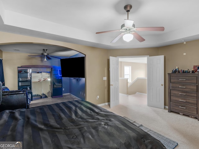 carpeted bedroom with ceiling fan and a tray ceiling