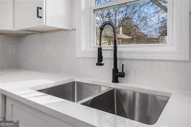 room details featuring white cabinetry, sink, and backsplash