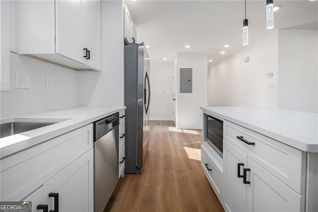 kitchen featuring white cabinetry, hanging light fixtures, stainless steel appliances, dark hardwood / wood-style floors, and electric panel