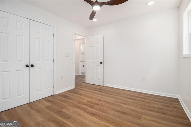 unfurnished bedroom featuring hardwood / wood-style flooring, ceiling fan, and a closet