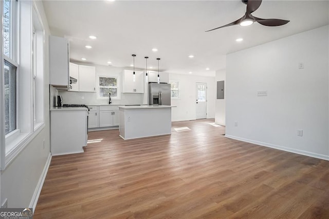 kitchen featuring a kitchen island, hardwood / wood-style floors, pendant lighting, white cabinets, and stainless steel fridge