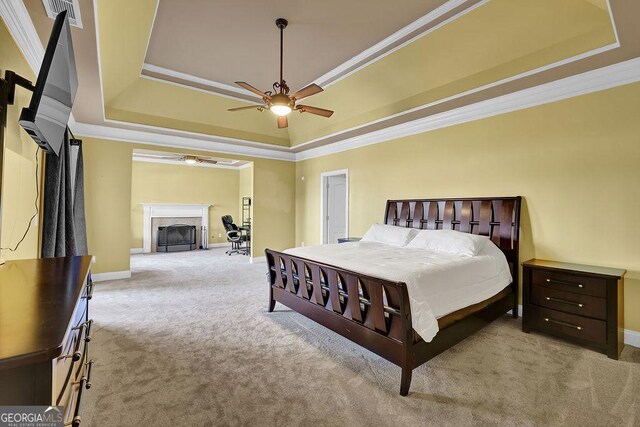 bedroom with ceiling fan, carpet, a tray ceiling, and ornamental molding