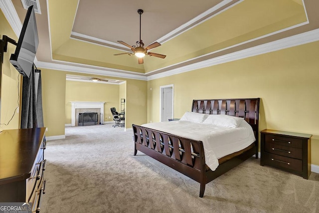 carpeted bedroom featuring a fireplace with flush hearth, ornamental molding, and a raised ceiling