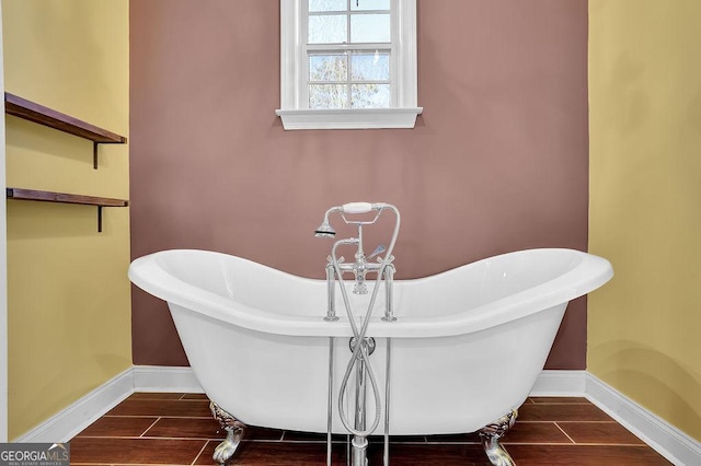 full bathroom with wood tiled floor, a freestanding tub, and baseboards