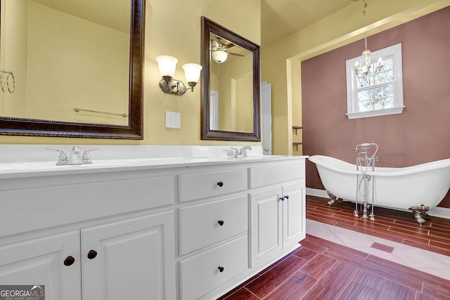 full bath featuring a notable chandelier, wood finish floors, a sink, a freestanding bath, and double vanity