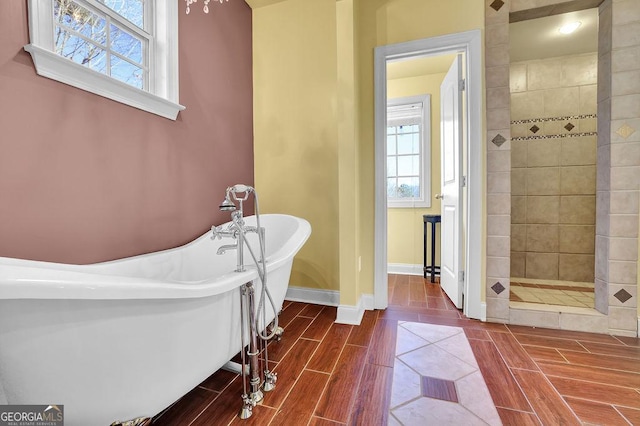 bathroom with a freestanding bath, tiled shower, wood finish floors, and baseboards