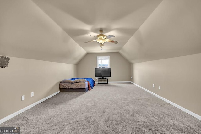 unfurnished bedroom featuring carpet, vaulted ceiling, baseboards, and ceiling fan