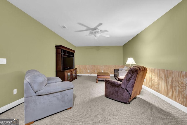 living room featuring light carpet, ceiling fan, and wooden walls