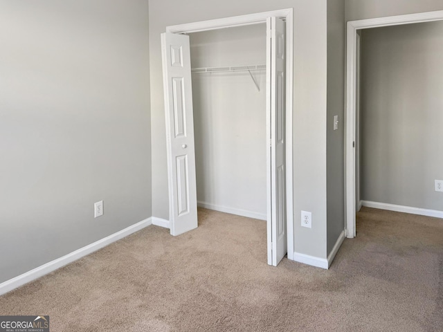 unfurnished bedroom featuring light carpet and a closet