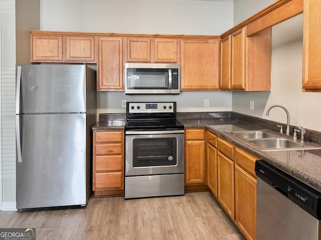 kitchen with appliances with stainless steel finishes, sink, and light hardwood / wood-style flooring