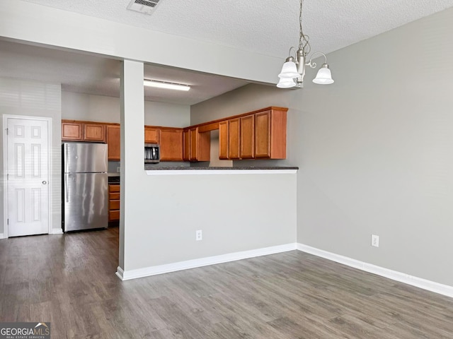 kitchen featuring dark hardwood / wood-style floors, a notable chandelier, stainless steel appliances, and pendant lighting