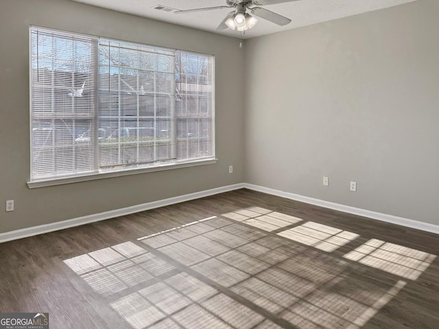 empty room with ceiling fan, a textured ceiling, dark hardwood / wood-style flooring, and a healthy amount of sunlight