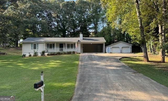 ranch-style home featuring an outbuilding, a garage, a front yard, and covered porch