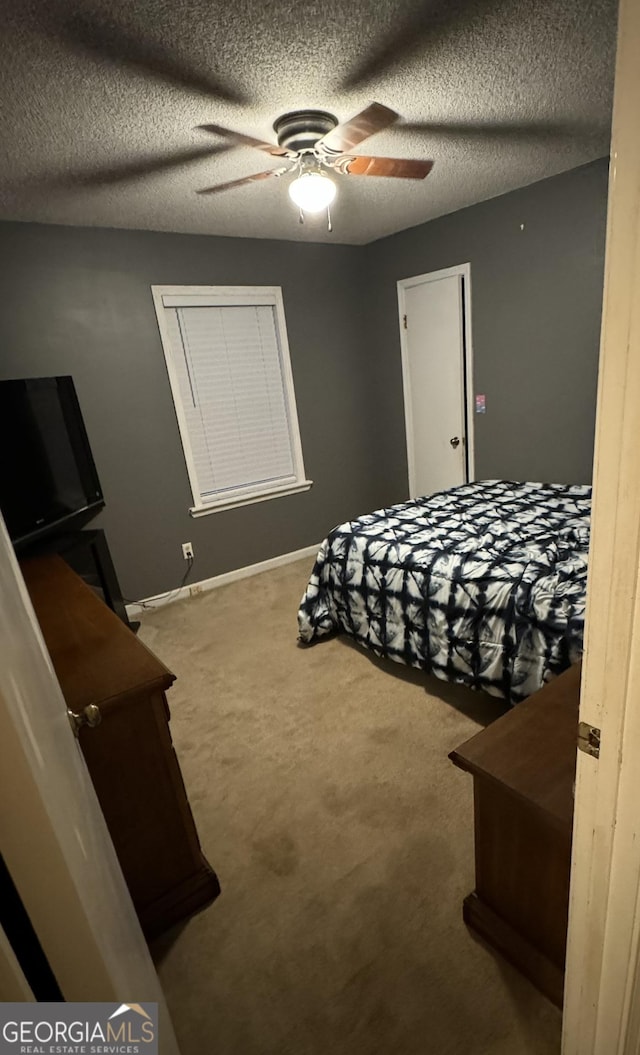 carpeted bedroom featuring ceiling fan and a textured ceiling