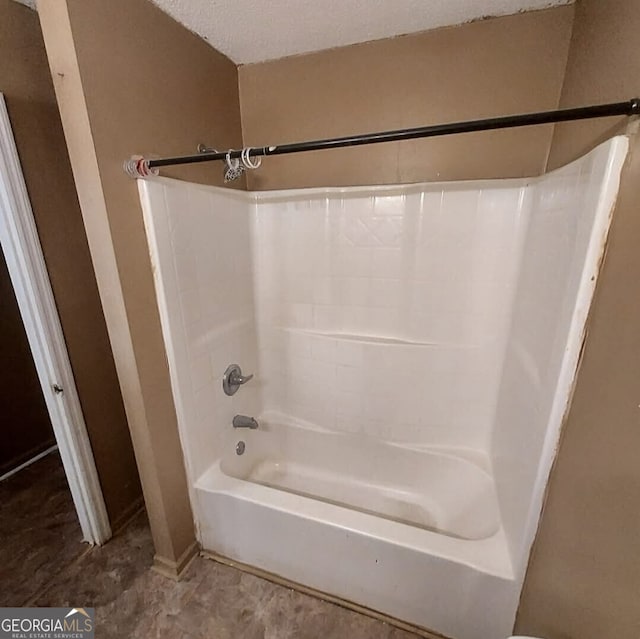 bathroom with a textured ceiling and tub / shower combination