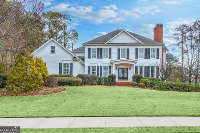 colonial home featuring a front lawn and french doors