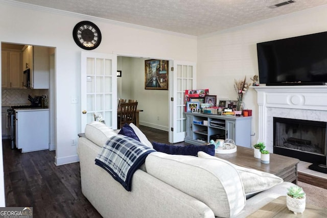 living room with dark wood-type flooring, a high end fireplace, a textured ceiling, and ornamental molding