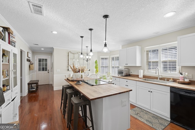 kitchen with white cabinets, black appliances, a center island, wood counters, and sink