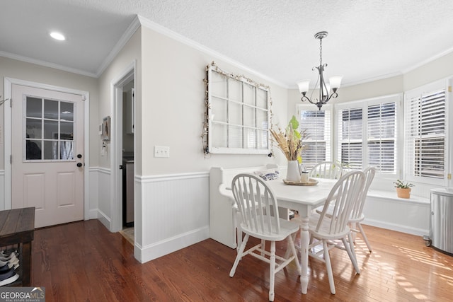 dining area with a textured ceiling, dark hardwood / wood-style flooring, crown molding, and a chandelier