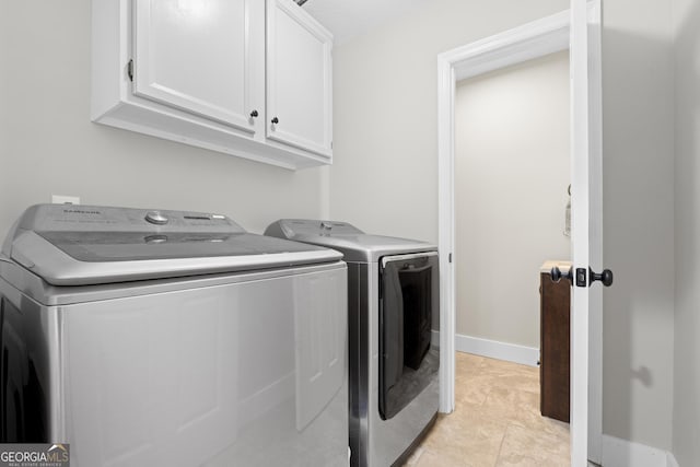 laundry area with light tile patterned flooring, separate washer and dryer, and cabinets