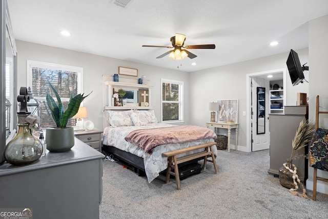 carpeted bedroom with ceiling fan, a spacious closet, and multiple windows