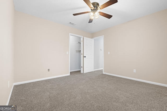 empty room featuring ceiling fan and carpet