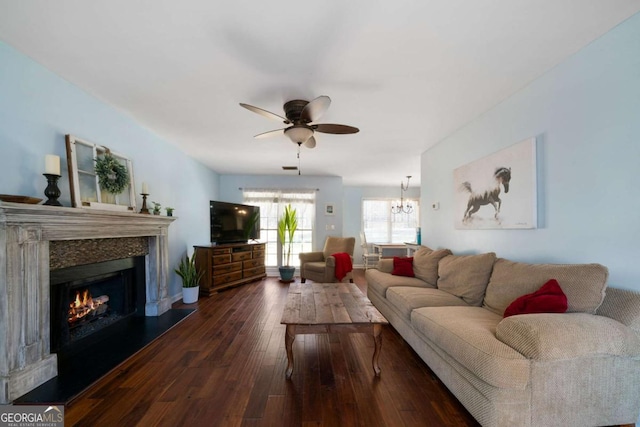 living room with dark hardwood / wood-style flooring and ceiling fan with notable chandelier