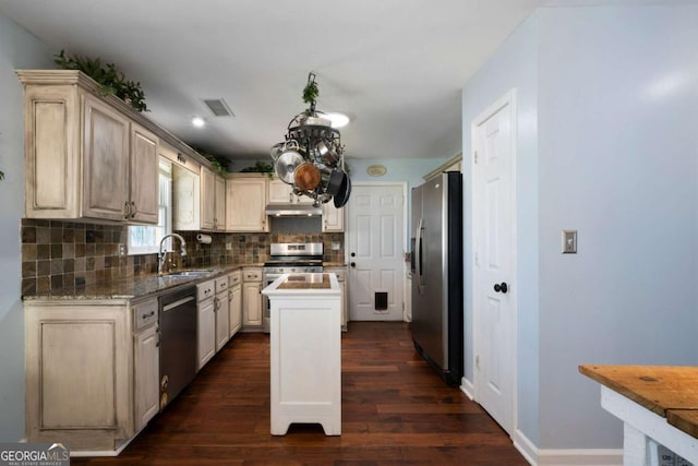 kitchen with cream cabinets, dark hardwood / wood-style floors, stainless steel appliances, and a kitchen island