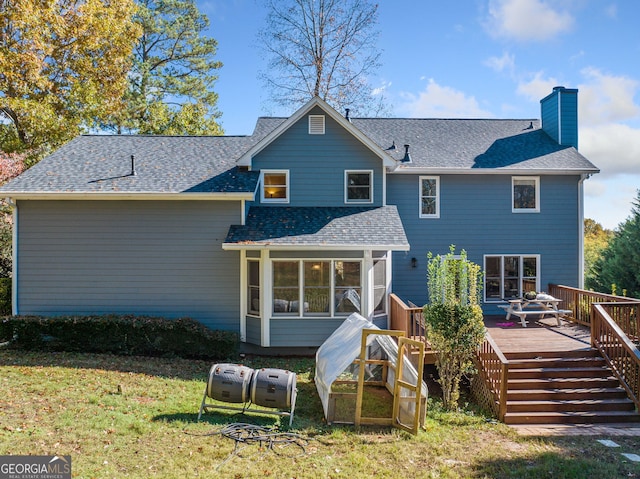 rear view of property with a wooden deck, a yard, and a sunroom