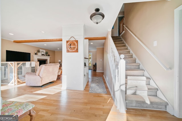 stairs with crown molding and wood-type flooring