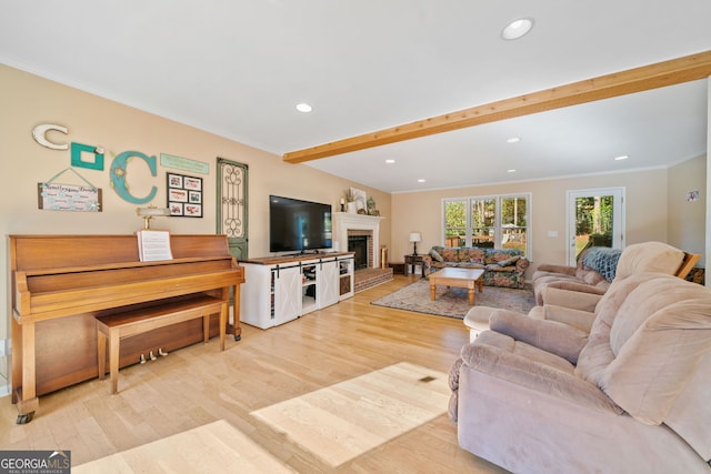 living room with ornamental molding, a brick fireplace, beam ceiling, and light hardwood / wood-style flooring