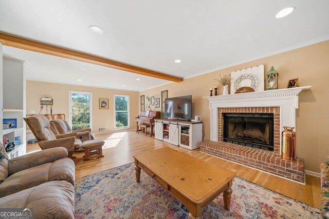 living room featuring a fireplace, ornamental molding, and light wood-type flooring